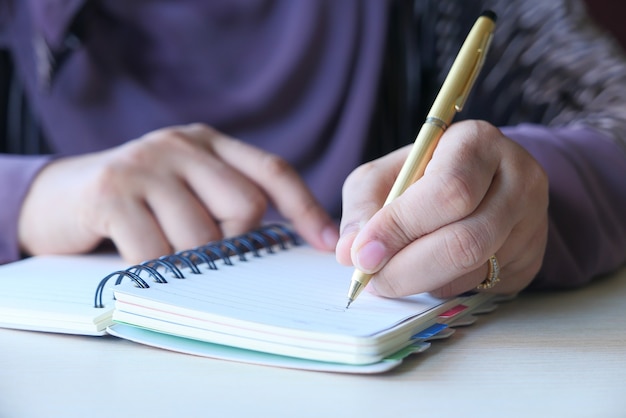 Gros plan de la main de femmes écrit sur le bloc-notes.