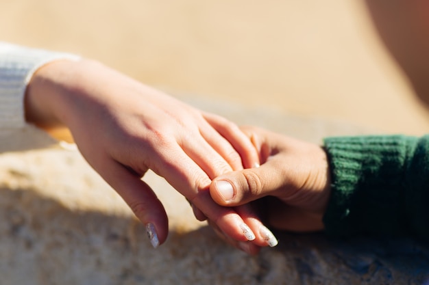 Gros plan sur la main d'une fille tenant la main d'un homme. Les ongles de la fille sont recouverts de vernis