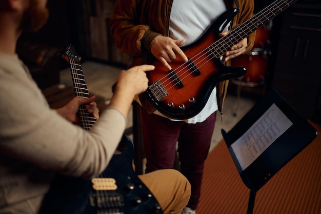 Gros plan sur la main floue d'un musicien masculin jouant de la guitare. Enseignant et étudiant à la leçon de musique