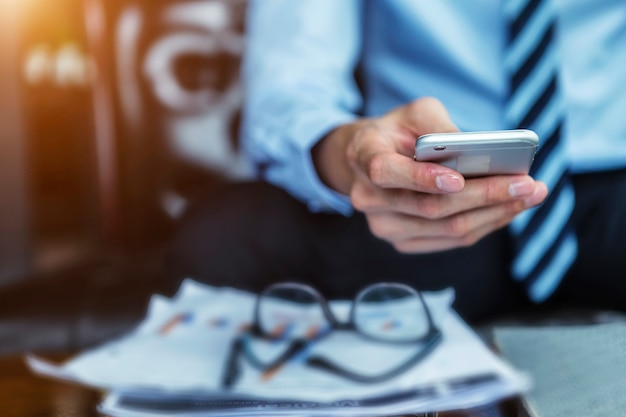 Gros plan de la main d&#39;homme d&#39;affaires détenant mobile dans le bureau.