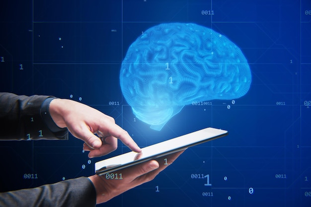 Gros plan d'une main d'homme d'affaires pointant vers une tablette avec un hologramme de cerveau bleu créatif sur fond flou Neurologie anatomie ai et concept d'apprentissage automatique