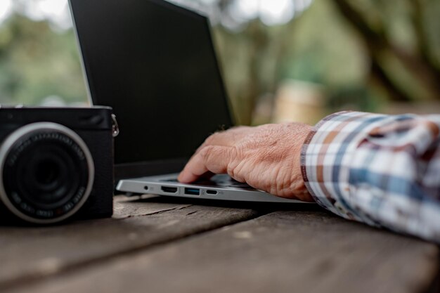 Gros plan sur la main d'un homme d'affaires tapant sur un ordinateur portable assis à l'extérieur dans le parc Concept de travail intelligent