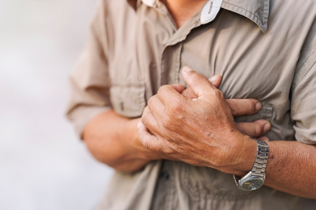 Gros plan sur la main d'un homme âgé qui lui tenait la poitrine douloureuse. Concept de maladie cardiaque.