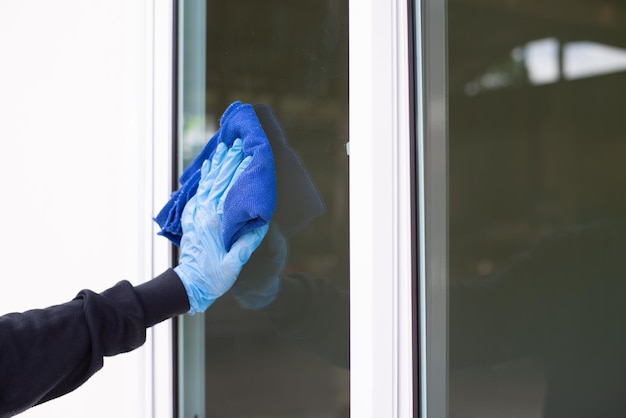 Gros plan sur une main d'homme nettoyant le verre de la fenêtre Nettoyage des fenêtres et des portes à la maison