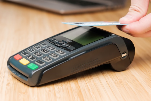Photo gros plan sur la main de l'homme payant avec une carte de crédit sans contact avec la technologie nfc à l'aide du paiement sans fil