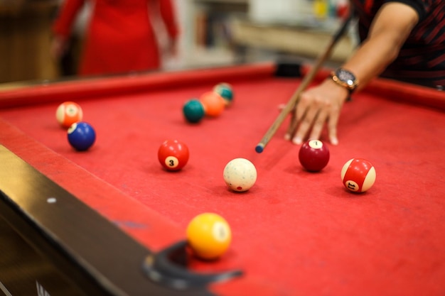 Gros plan sur la main d'un homme se préparant à tirer sur la boule blanche avec un ensemble complet de boules de billard