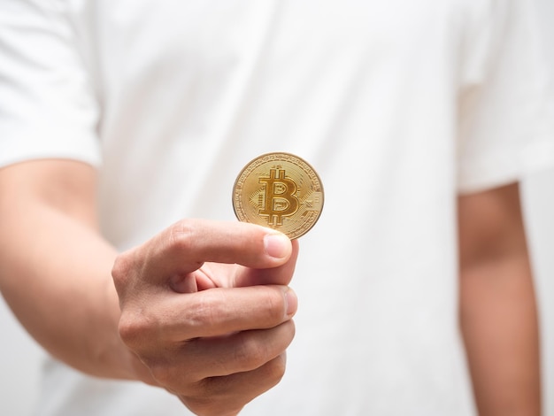 Gros plan main d'homme tenant de l'argent numérique bitcoin doré
