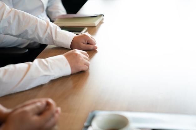 Gros plan sur la main des hommes d'affaires, ils parlent ensemble sur la table en bois l'après-midi