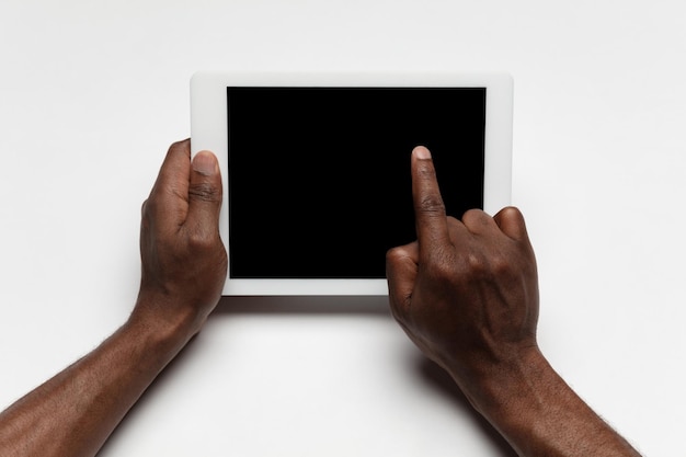 Gros plan sur une main humaine à l'aide d'une tablette avec un écran noir vierge, un concept d'éducation et d'entreprise