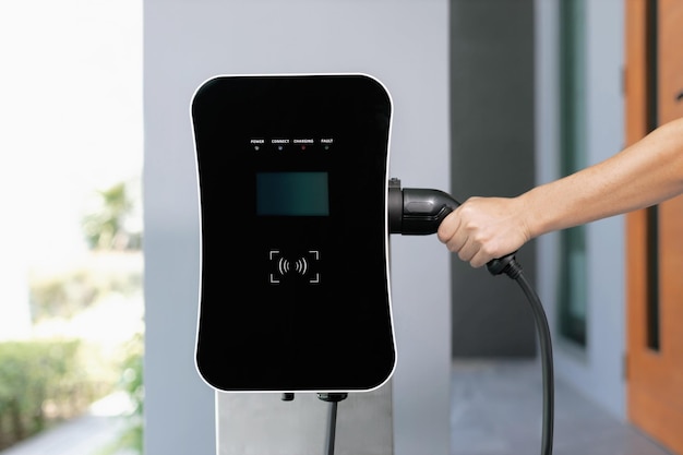 Gros plan de la main insérez la prise EV dans la voiture électrique progressive à la station de charge