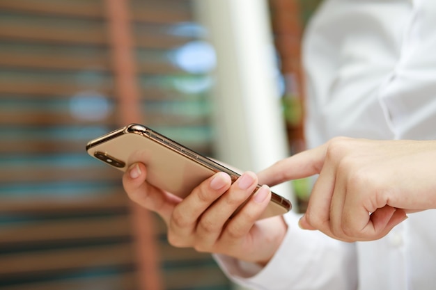 Gros plan main jeune femme en regardant un message sur un téléphone intelligent mobile pendant la pause en utilisant des téléphones portables pour communiquer dans le monde en ligne avec un écran noir vide ou vide