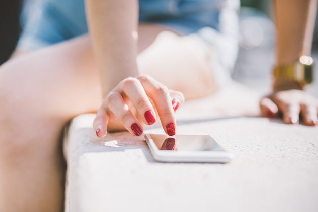 Gros plan sur la main de la jeune femme en tapant sur l&#39;écran d&#39;un téléphone intelligent