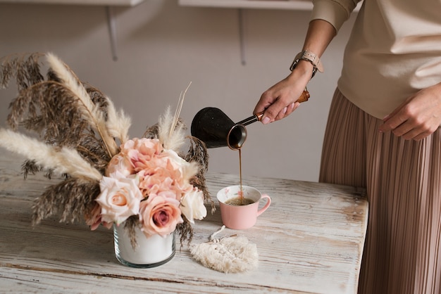 Gros plan de la main de la jeune femme, verser le café d'un moka dans une tasse - matin, petit-déjeuner, concept de pause