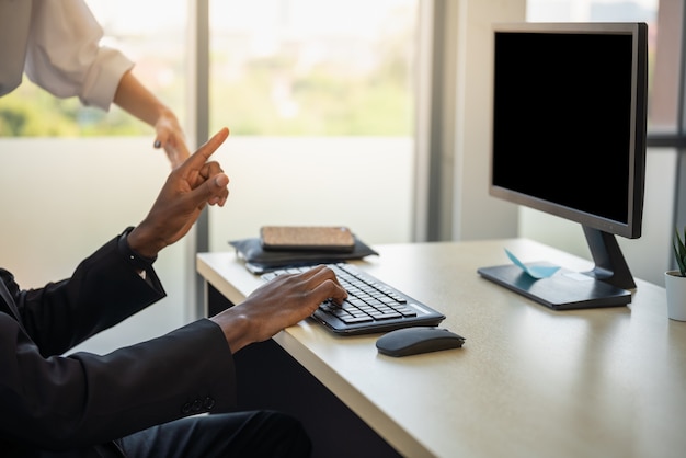 Gros plan de la main de jeune homme d'affaires africain travaillant avec ordinateur et clavier au bureau.