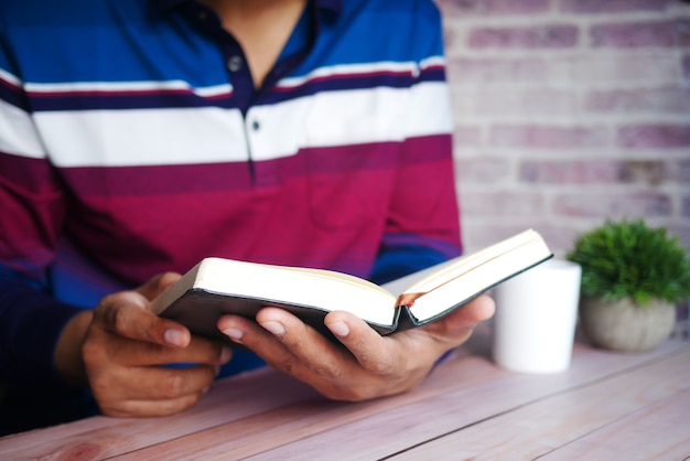 Photo gros plan sur une main de jeune homme lisant un livre