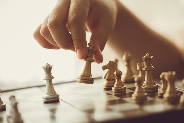 Gros plan main jouant aux échecs en déplaçant la pièce d'échecs en avant