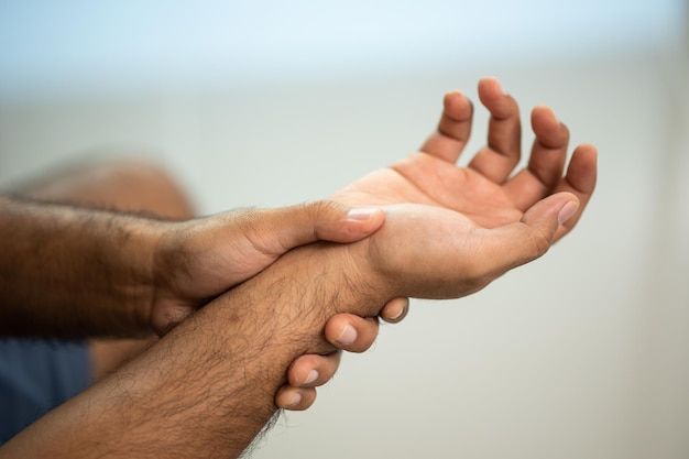 Gros plan sur une main masculine blessée et douloureuse à la main, au poignet. Symptôme du syndrome du bureau. Il a des symptômes de stress dans sa raideur de la main causant des désagréments.