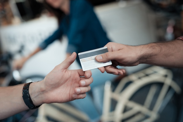 Gros plan d'une main masculine donne une carte de crédit au vendeur.