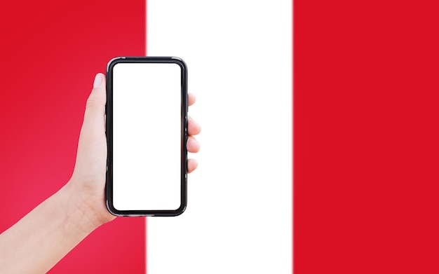 Gros plan d'une main masculine tenant un smartphone avec un blanc à l'écran sur fond de drapeau flou du Pérou