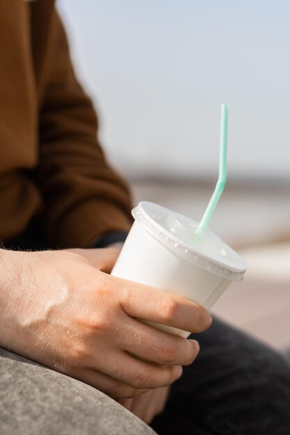 Gros plan d'une main masculine tenant une tasse de café en papier