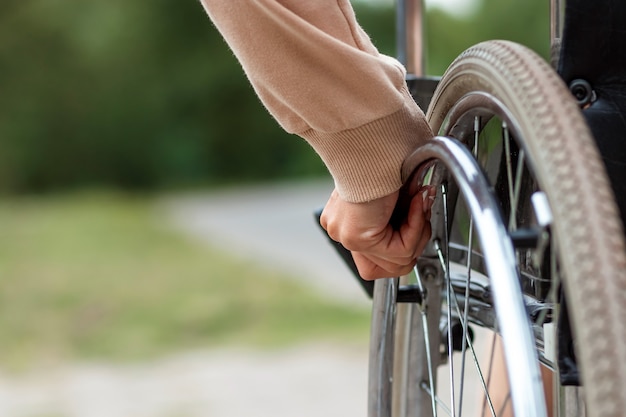 Gros plan d'une main sur une roue de fauteuil roulant. Le concept d'un fauteuil roulant, d'une personne handicapée, d'une vie pleine, d'une personne paralysée, handicapée, d'une vie heureuse.