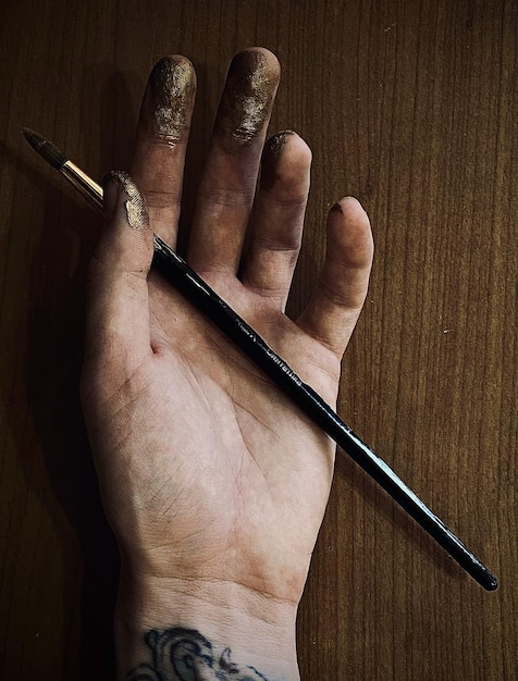 Gros plan de la main d'un tatoueur tenant un pinceau