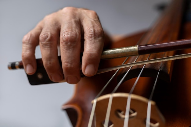 Gros plan de la main tenant l'archet au talon et placé correctement sur la corde G sur le violoncelle Instrument d'orchestre Concept et étudiant en musique