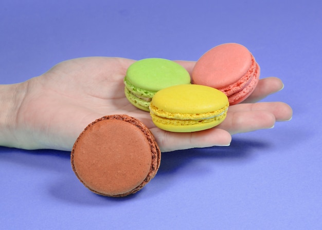 Gros plan de la main tenant des macarons colorés