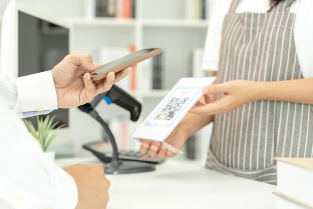 Gros plan sur une main tenant un smartphone et scannant le paiement par code QR