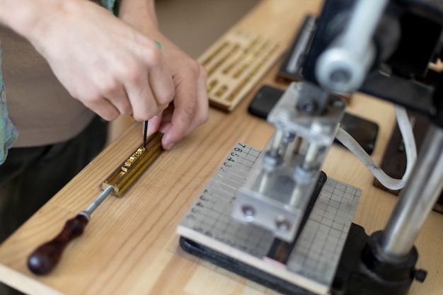 Gros plan sur les mains d'un artisan en tapant du texte pour le cuir de marque avec un tampon personnel créant une étiquette d'artisanat