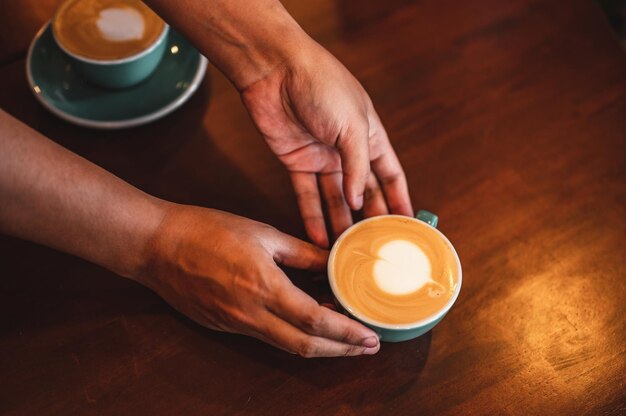 Gros plan des mains barista homme servant du café dans un café. mains masculines plaçant une tasse de café sur la table. Café, barista, extraction, service, café, concept de style de vie.