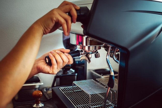 Gros plan des mains de Barista préparant une machine à café automatique pour faire du café dans un café