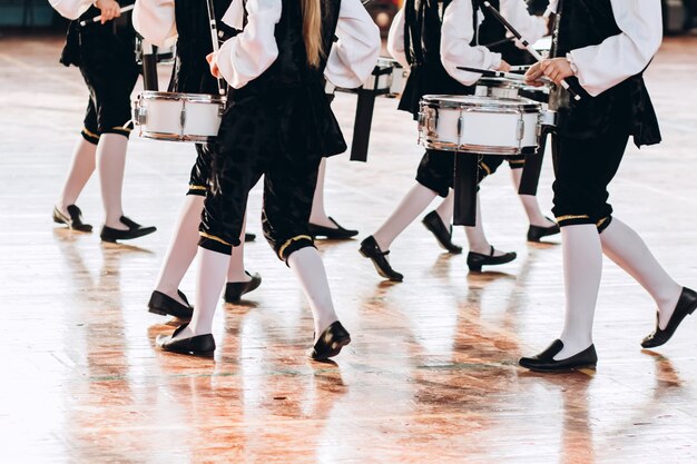 Un gros plan des mains d'un batteur lors d'un défilé. Ensemble pour enfants en chemises blanches. Caisse claire neuve blanche, bâtons blancs. Le concept d'un défilé militaire et mars.