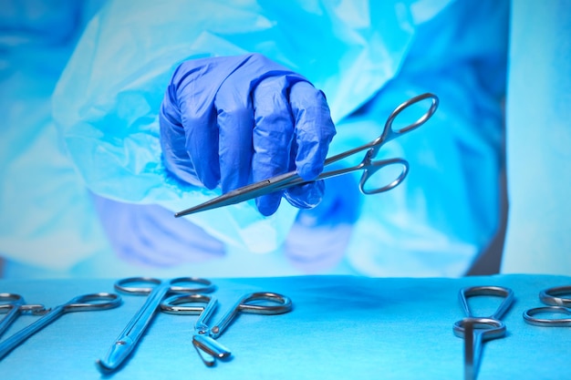 Gros plan des mains des chirurgiens au travail dans la salle d'opération en bleu. Équipe médicale effectuant une opération