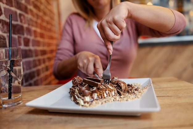 Gros plan sur des mains coupant des crêpes dans une crêperie