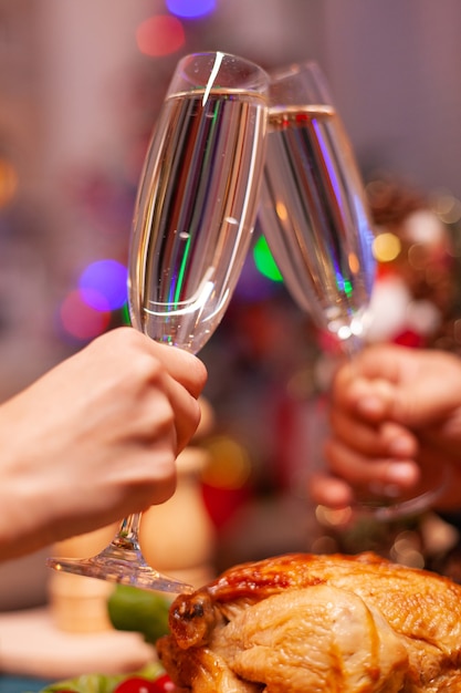 Gros plan des mains de couples frappant le verre de vin pendant le dîner de Noël