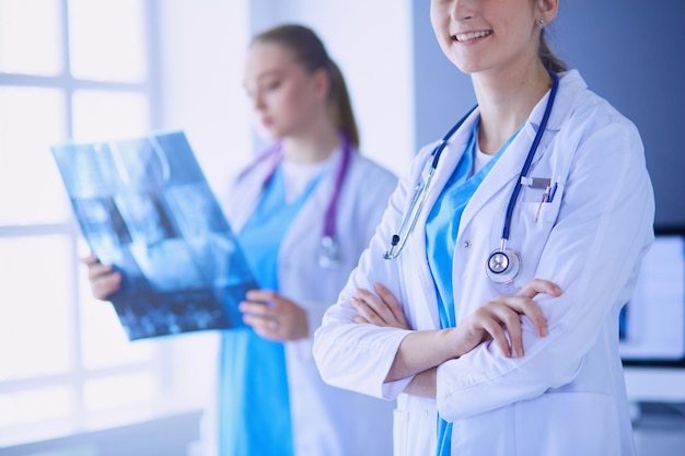 Gros plan sur les mains croisées du médecin et son collègue avec radiographie en arrière-plan.