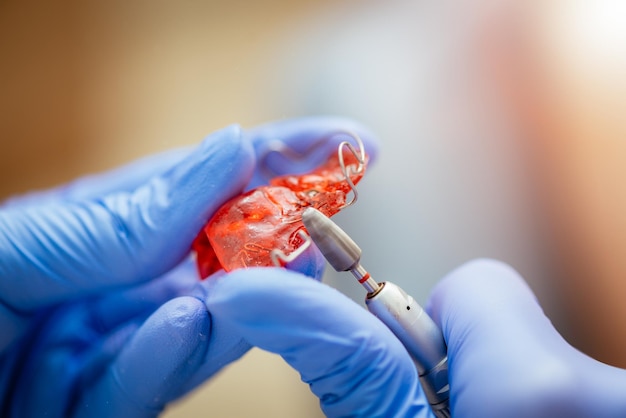 Gros plan sur les mains d'un dentiste faisant une correction sur une prothèse mobile.