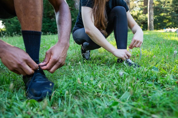 Gros plan des mains de deux sportifs attachant leurs chaussures, photo avec espace de copie