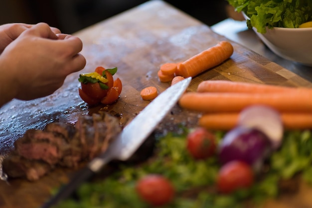 gros plan des mains du chef dans la cuisine de l'hôtel ou du restaurant préparant un steak de boeuf avec une décoration végétale