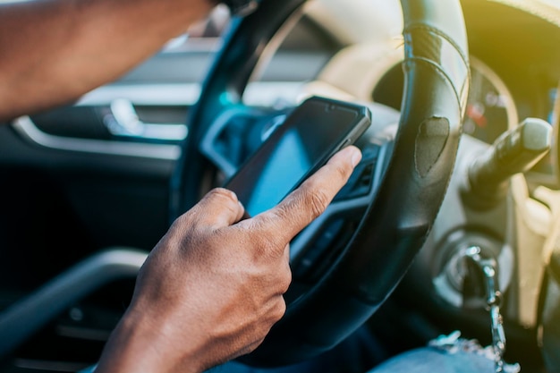 Gros plan sur les mains du conducteur à l'aide de son téléphone Personne dans sa voiture à l'aide d'un téléphone portable Concept mains du conducteur touchant l'écran du téléphone portable