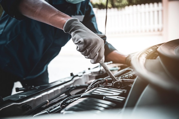 Gros plan sur les mains du mécanicien automobile utilisant la clé pour entretenir le moteur de la voiture