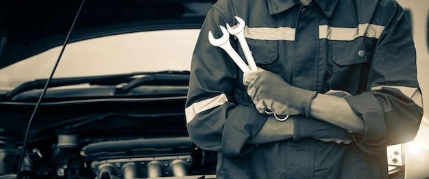 Photo gros plan sur les mains du mécanicien automobile utilisant la clé pour entretenir le moteur de la voiture