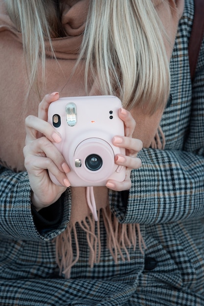 Gros plan des mains féminines avec appareil photo rose Instax