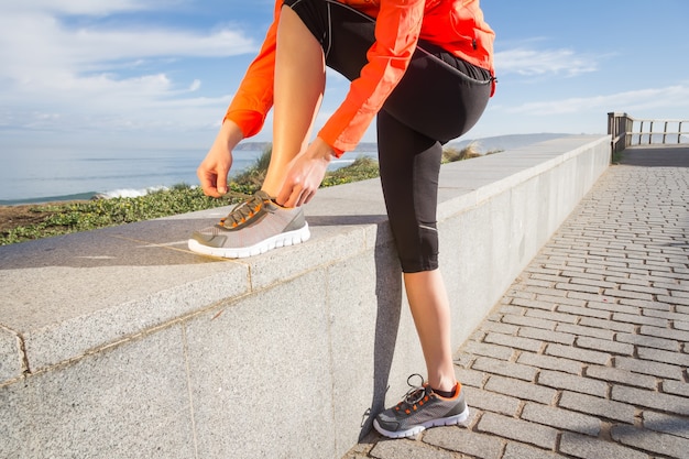 Gros plan des mains féminines attachant des lacets de chaussures de course