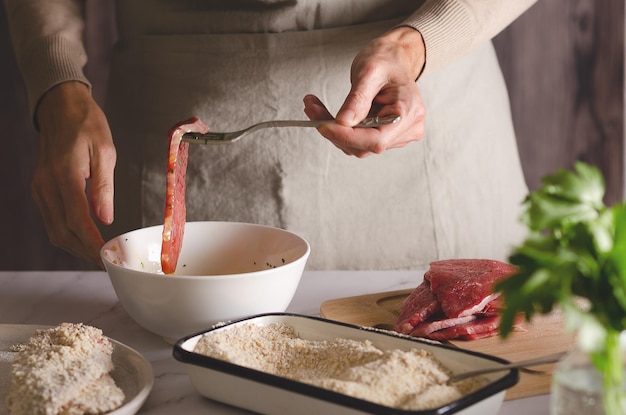 Gros plan sur des mains féminines cuisinant des milanesas argentines dans la cuisine à la maison