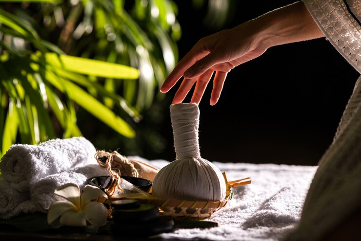 Photo gros plan: mains féminines tenant une boule à base de plantes chaude pour un massage thaï