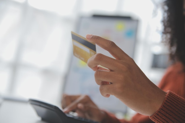 Gros plan des mains féminines tenant une carte de crédit et un smartphone jeune femme payant en ligne à l'aide d'un service bancaire entrant des informations achats commande dans une boutique internet faisant un paiement sécurisé