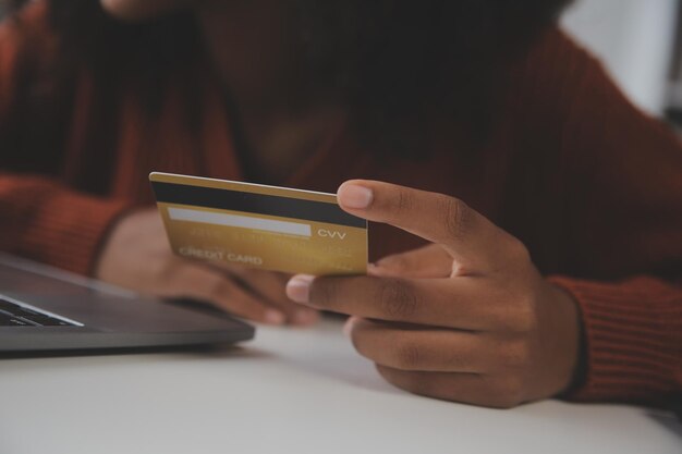 Gros plan des mains féminines tenant une carte de crédit et un smartphone jeune femme payant en ligne à l'aide d'un service bancaire entrant des informations achats commande dans une boutique internet faisant un paiement sécurisé