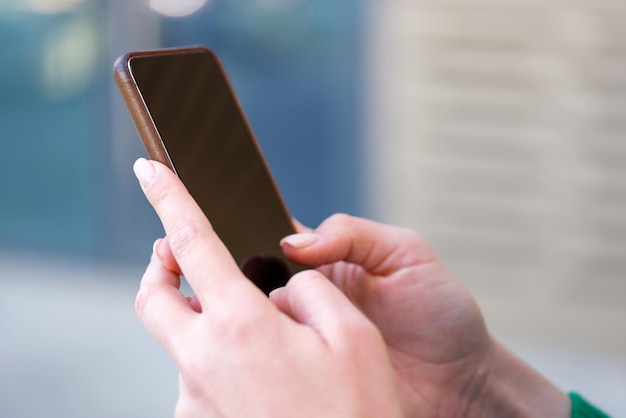 Gros plan de mains féminines tenant un espace de copie de téléphone portable moderne sur un écran vide femme surfant